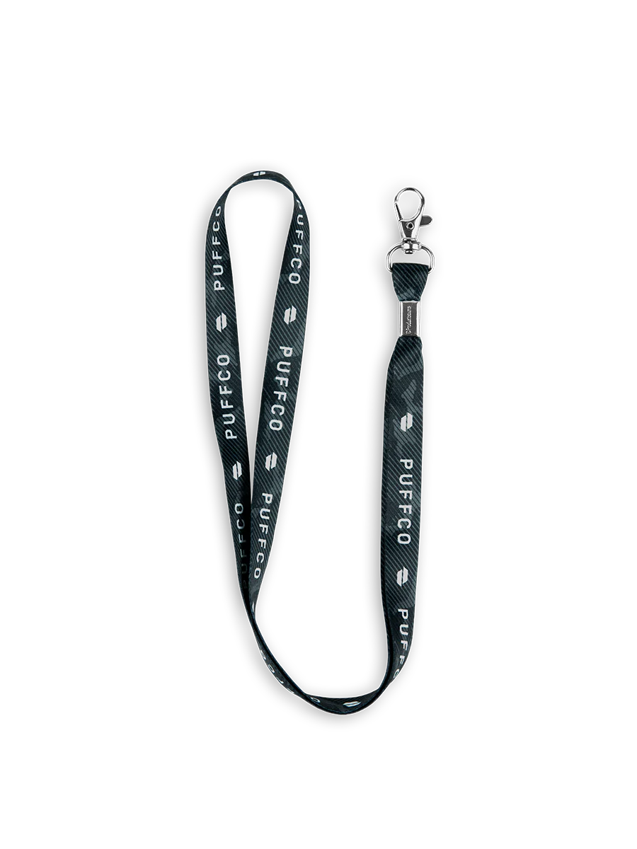 Black Puffco lanyard with white branding, a subtle tie-dye pattern, and a silver metal clasp.